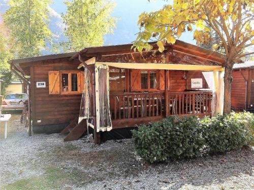 a small wooden cabin with a porch and a canopy at Ferienhaus in Porlezza mit Terrasse und gemeinsamem Pool in Porlezza