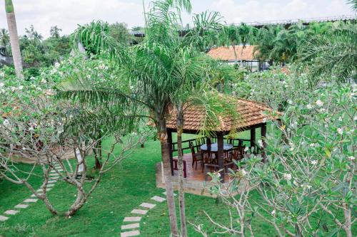 a house in a garden with a palm tree at NGOC THU HOTEL in Soc Trang