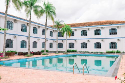 a building with a swimming pool in front of a building with palm trees at NGOC THU HOTEL in Soc Trang