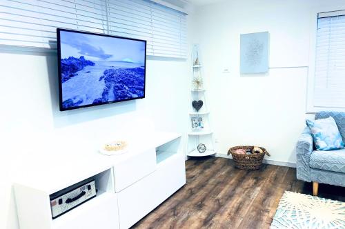 a living room with a flat screen tv on a wall at 100m to Beach&Shop Spacious Pristine One Story Family Home in Batemans Bay