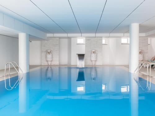 a swimming pool with blue water in a white room at MH Peniche in Peniche