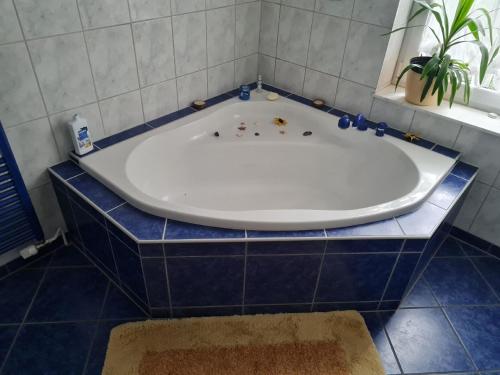 een groot bad in een badkamer met blauwe tegels bij Appartement in WeißwasserOberlausitz mit Großem Garten in Weißwasser