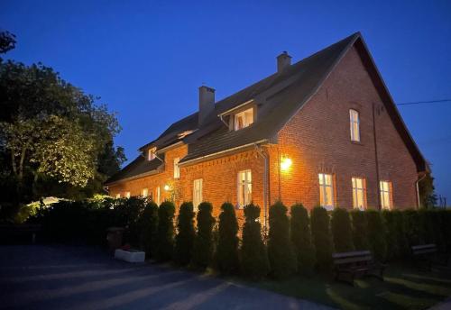 Une grande maison en brique éclairée la nuit dans l'établissement Schönes antikes Haus an der Ostsee in Mielno, à Mielenko