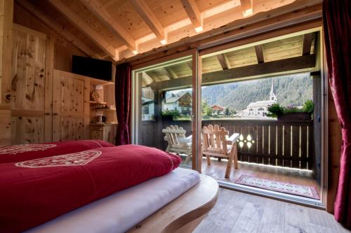 a bedroom with a bed and a large window at La Ücia by Fana Ladina in San Vigilio Di Marebbe