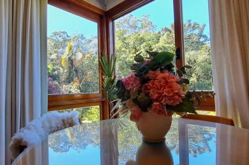 a vase of flowers sitting on a table in front of a window at Melhor localização de Gramado in Gramado