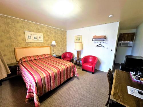 um quarto de hotel com uma cama e duas cadeiras vermelhas em Red Top Motor Inn em Iron Bridge