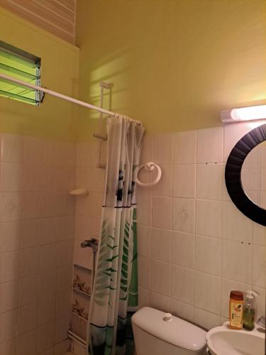 a bathroom with a toilet and a shower curtain at Résidence Les Manguiers in Pointe-Noire