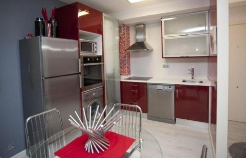 a kitchen with red cabinets and a stainless steel refrigerator at Ferienwohnung für 4 Personen ca 45 qm in Santiago de Compostela, Galicien Binnenland von Galicien in Santiago de Compostela
