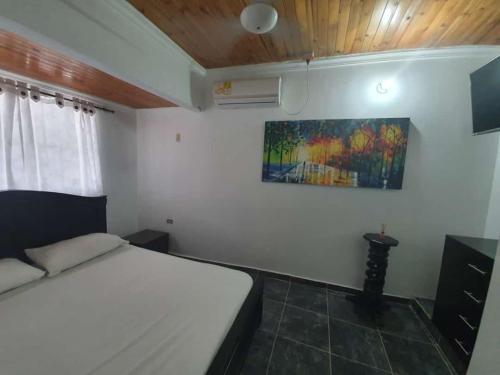1 dormitorio con 1 cama y una pintura en la pared en El rancho de arnolis, en Cereté