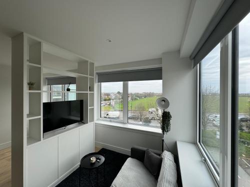 a living room with a couch and a tv and windows at London LuXXe Suites & Apartments - London Heathrow Airport, Terminal 1 2 3 4 5 in New Bedfont