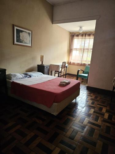 a bedroom with a bed with a red blanket on it at Varzea Palace Hotel in Teresópolis
