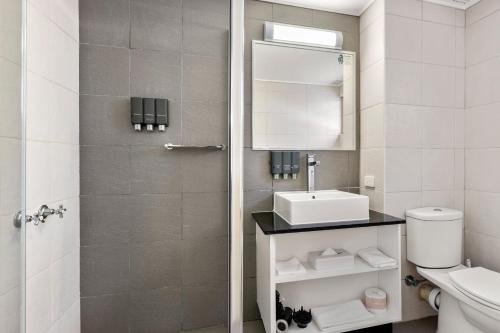 a bathroom with a toilet and a sink and a mirror at Zebra Motel in Coffs Harbour