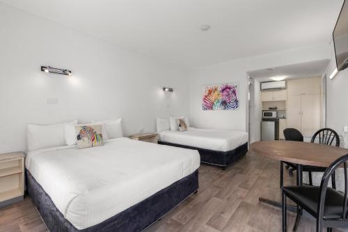 a hotel room with two beds and a table at Zebra Motel in Coffs Harbour