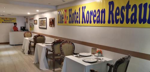 een restaurant met witte tafels en stoelen en een bar bij The E-Hotel Makati in Manilla