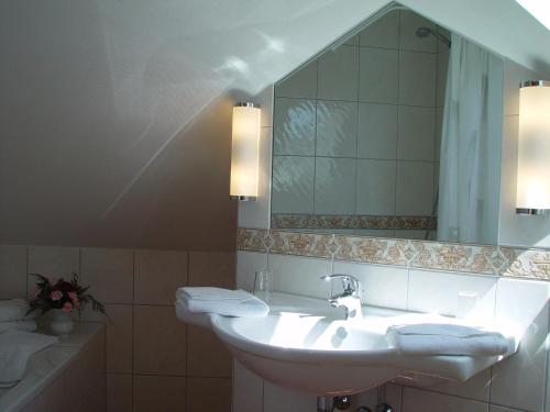 a bathroom with a sink and a mirror and a tub at Hotel Ostseeblick in Ostseebad Karlshagen