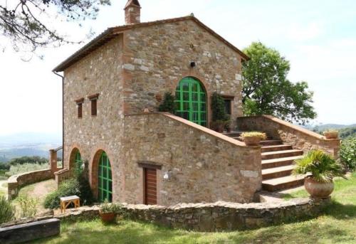 un gran edificio de piedra con ventanas verdes y escaleras en Wohnung auf zwei Etagen mit Studio und mit Balkonblick ins bergige Grüne, en Monte Vibiano Vecchio