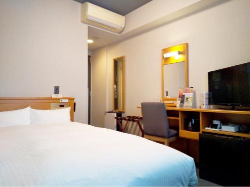 a hotel room with a bed and a desk and a television at Hotel Route-Inn Mikawa Inter in Hakusan