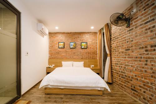 a bedroom with a white bed and a brick wall at King Kong Homestay in Ninh Binh