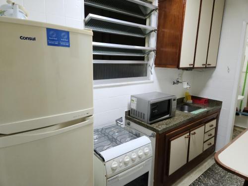 a small kitchen with a refrigerator and a microwave at Lindo apartamento em Icaraí perto de tudo. in Niterói