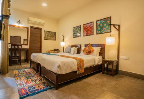 a bedroom with a bed and a table and a desk at Tripli Hotels Shambhu Villas in Udaipur