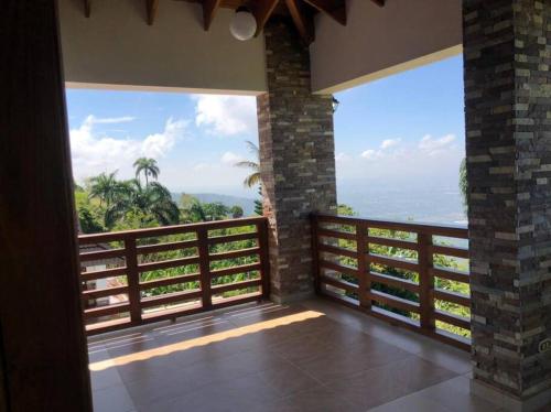 a room with a balcony with a view of the ocean at Villa Santiago , La Loma de Ranchito Pichey in Santiago de los Caballeros