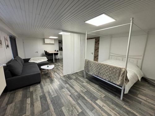1 dormitorio con cama, sofá y mesa en Chaleureux Appartement - Estrade, en Bollwiller