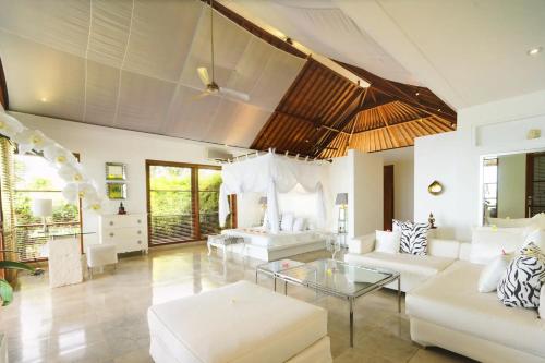 a living room with white furniture and a glass table at Shunyata Villas Bali in Seraya
