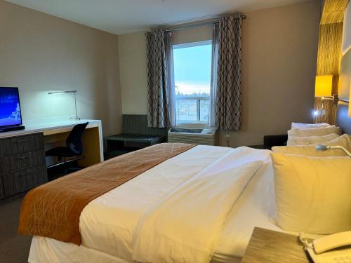 a hotel room with a large bed and a window at Southfort Inn in Fort Saskatchewan