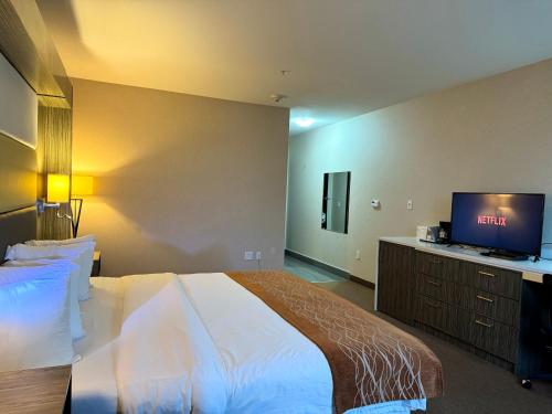 a bedroom with a bed and a flat screen tv at Southfort Inn in Fort Saskatchewan