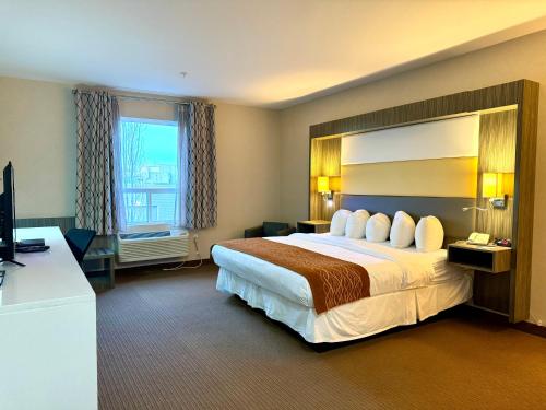 um quarto de hotel com uma cama grande e uma televisão em Southfort Inn em Fort Saskatchewan