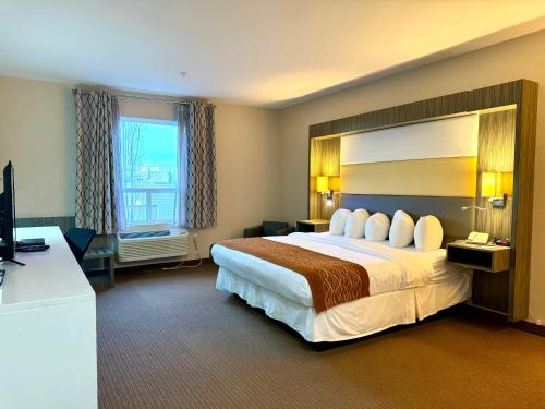 a hotel room with a large bed and a television at Southfort Inn in Fort Saskatchewan