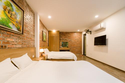 um quarto com 2 camas e uma parede de tijolos em King Kong Homestay em Ninh Binh