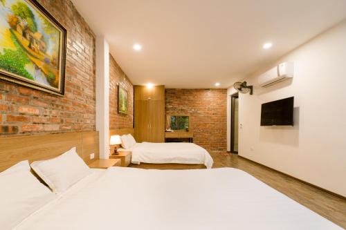 a bedroom with two beds and a brick wall at King Kong Homestay in Ninh Binh