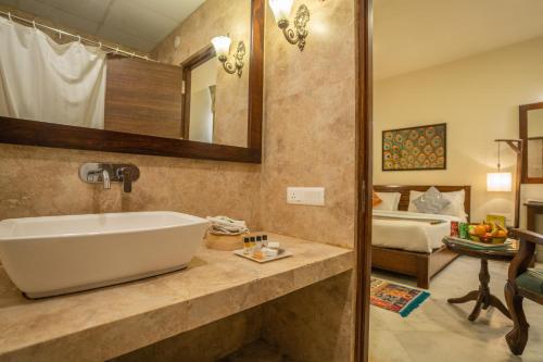 a bathroom with a large sink and a bedroom at Tripli Hotels Shambhu Villas in Udaipur