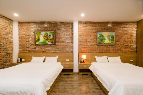 a bedroom with two beds and a brick wall at King Kong Homestay in Ninh Binh
