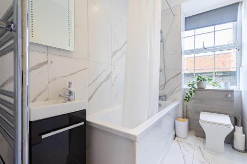 a white bathroom with a sink and a toilet at Cosy Central 2 Bedroom - Near Brighton Beach & Shops! in Brighton & Hove