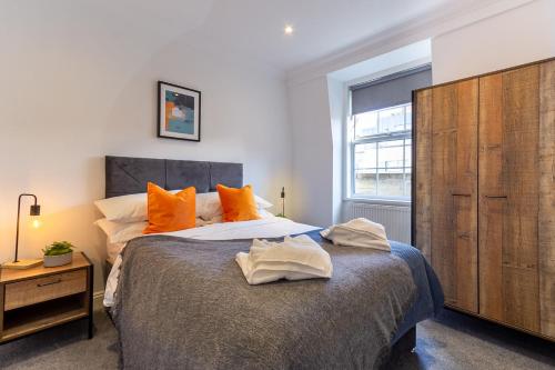 a bedroom with a large bed with orange pillows at Cosy Central 2 Bedroom - Near Brighton Beach & Shops! in Brighton & Hove