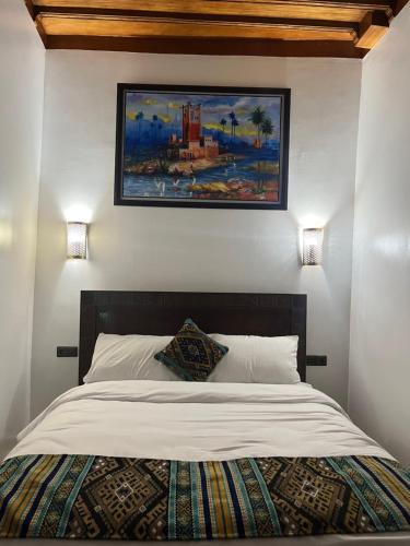 a bedroom with a bed with a painting on the wall at Riad el wazania in Rabat