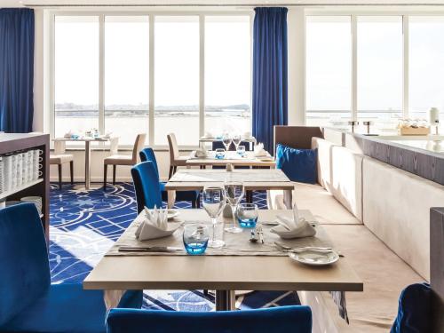 a restaurant with tables and chairs and windows at MH Peniche in Peniche