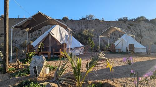 a group of tents in the dirt near a mountain at La Window Glamping in La Ventana