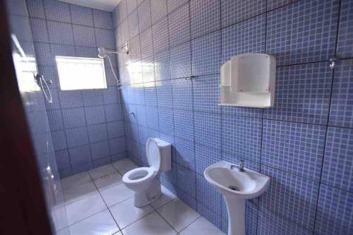 a blue tiled bathroom with a toilet and a sink at Recanto Minas a Goiás in Ceres