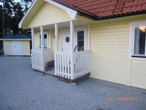 Casa pequeña con porche y valla blanca en Großes Ferienhaus auf Gotland 700 Meter zum Meer en Ljugarn