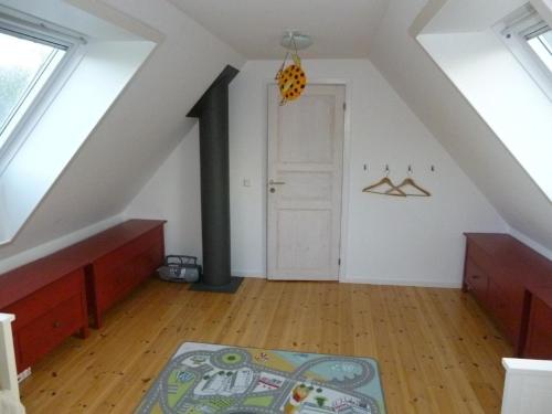 Habitación en el ático con puerta blanca y alfombra en Großes Ferienhaus auf Gotland 700 Meter zum Meer en Ljugarn