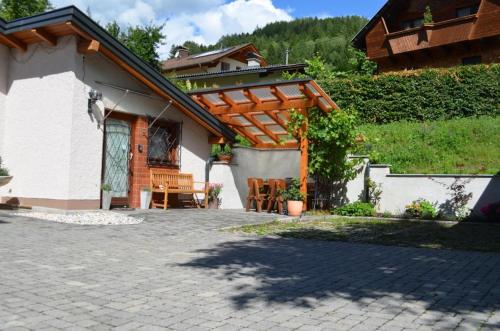 un patio de una casa con pérgola de madera en Charmante Ferienwohnung in Gemeinde Flattach mit Beheiztem gemeinsamem Pool, en Flattach