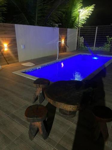 a pool with a table and stools in front of it at Casa de praia em Japaratinga.(Pé na areia!) in Japaratinga