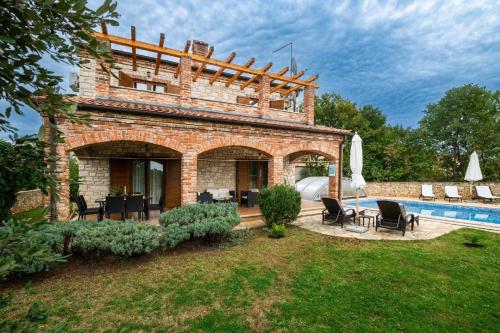 een bakstenen huis met een zwembad in een tuin bij Villa Wish mit beheiztem Pool in Svetvinčenat