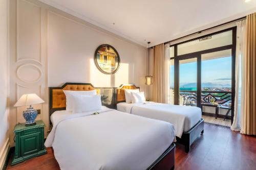 2 bedden in een hotelkamer met een balkon bij Hadana Boutique Resort HoiAn - former Belle Maison Hadana HoiAn in Hội An