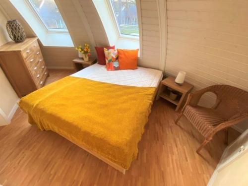 een kleine slaapkamer met een bed met een gele deken bij Tamika - Kugelhaus am See in Penzlin