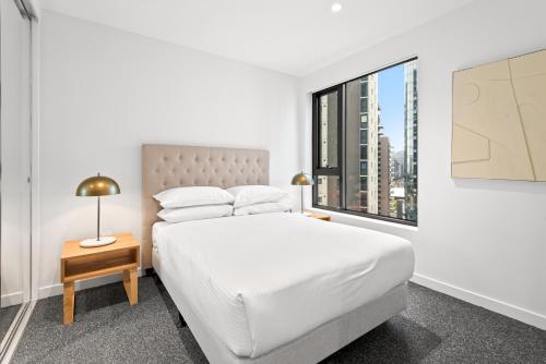 een slaapkamer met een wit bed en een raam bij Chic 2-Bed Inner-City Abode with BBQ, Gym & Pool in Melbourne