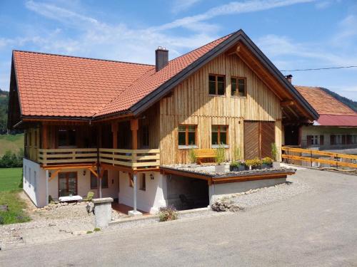 a large wooden house with a red roof at Direkt am Waldrand gelegene Ferienwohnung, ideal für Wanderer im Sommer und Wintersportler in der kalten Jahreszeit in Oberstaufen